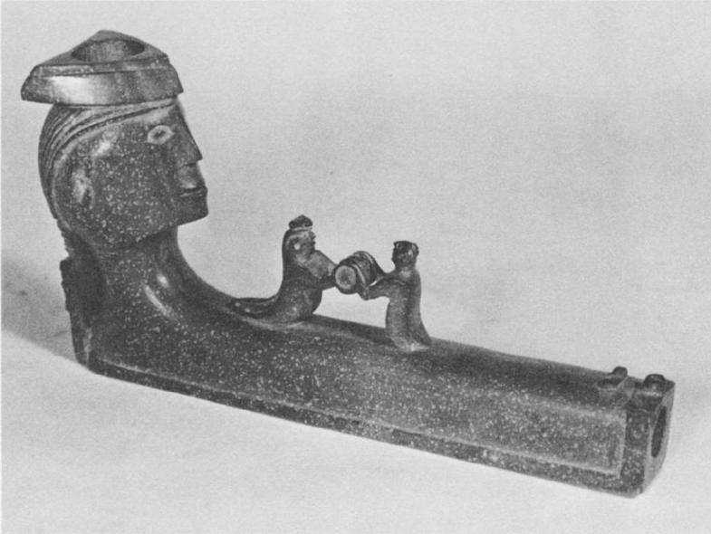 Трубка из катлинита с человеческой головой, вырезанной на шаре и двумя человеческими фигурками; длинна 5". Wyandot (Museum of the American Indian, #21/3037). (Фотография, M.A.I. Heye Foundation) 